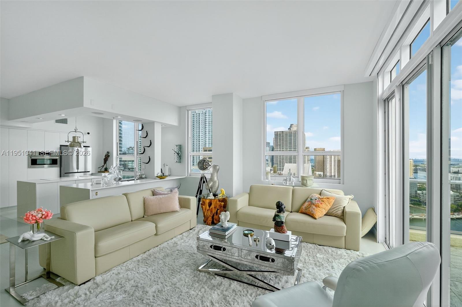 A bright living room features two beige sofas, a mirrored coffee table, and city views — 1155 Brickell Bay Dr, Miami FL 33131, MIAMI, FL