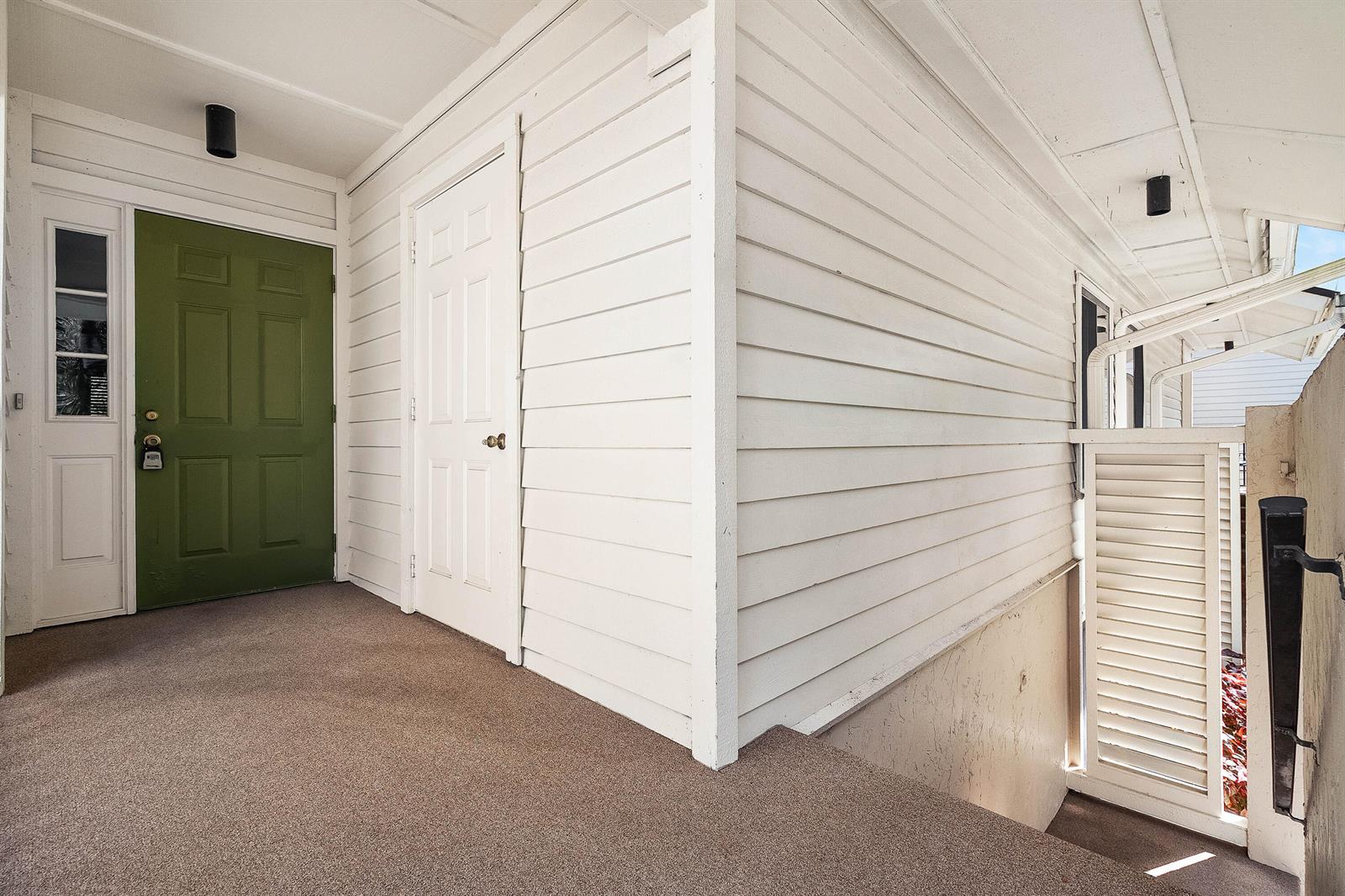 An exterior view of a building entrance featuring a green door and white siding — 6403 SE Brandywine Court # 223, Stuart FL 34997, STUART, FL