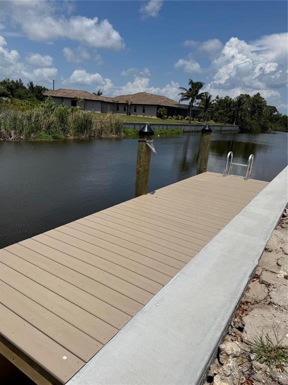A wooden dock with a metal ladder extends into a canal near a residential home — 13156 AMARYLLIS CIRCLE, PORT CHARLOTTE, FL
