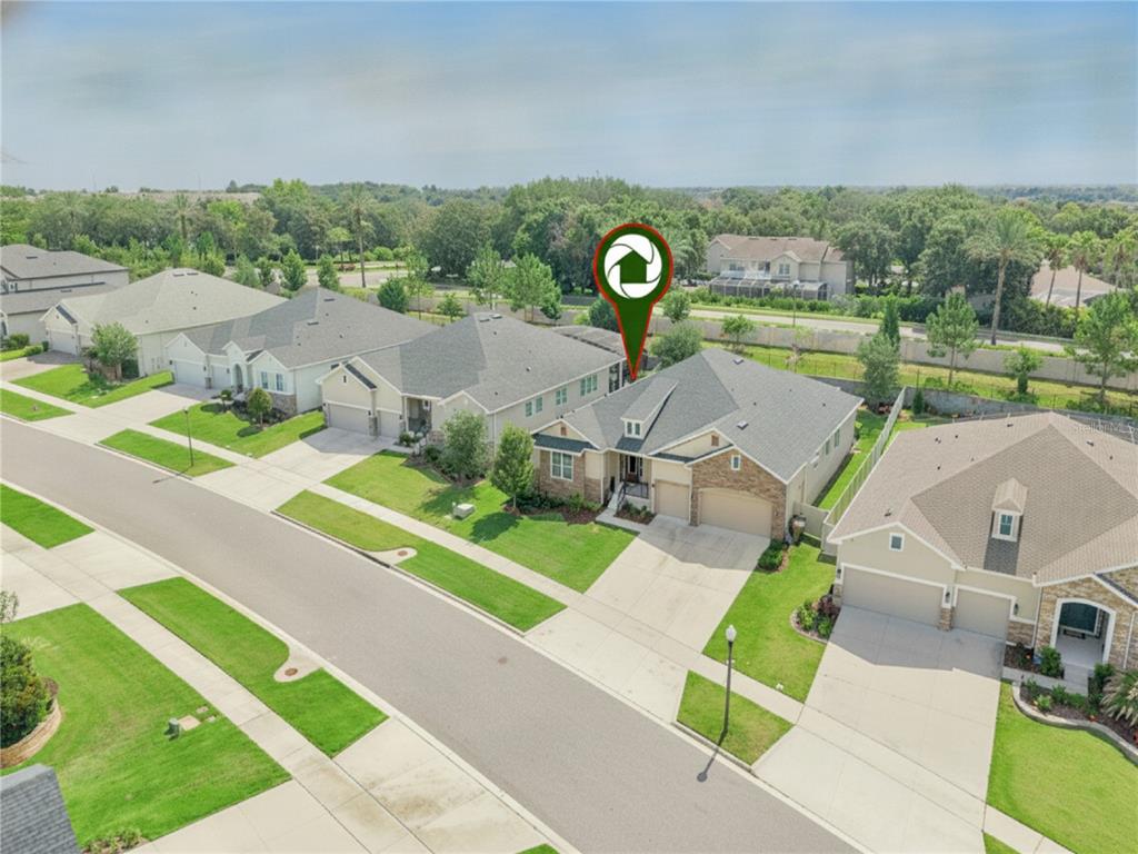 An aerial view shows a suburban street with several single-family homes and manicured lawns — 17286 HICKORY WIND DRIVE, CLERMONT, FL