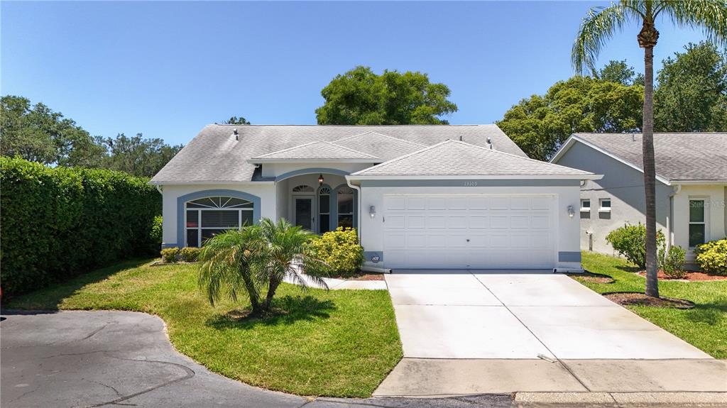 A single-story suburban house with a white garage, arched entryway, and a palm tree — 13109 DOBREE PLACE UNIT 29, RIVERVIEW, FL