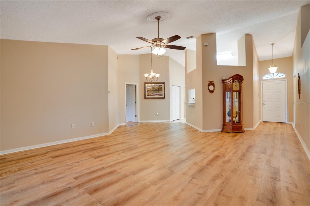 A spacious living area features light wood-look flooring, vaulted ceilings, and a tall grandfather clock — 13109 DOBREE PLACE UNIT 29, RIVERVIEW, FL