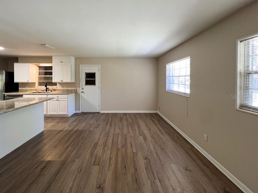 A kitchen with white cabinets and granite countertops opens into a living area with wood-look flooring — 2110 NW 54TH TERRACE, GAINESVILLE, FL