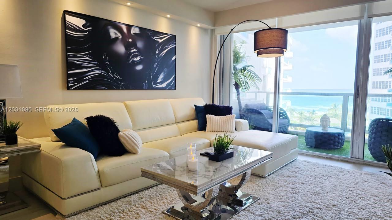 A modern living room features a white sectional sofa, a glass coffee table, and ocean views — 5151 Collins Ave # 726, Miami Beach FL 33140, MIAMI BEACH, FL