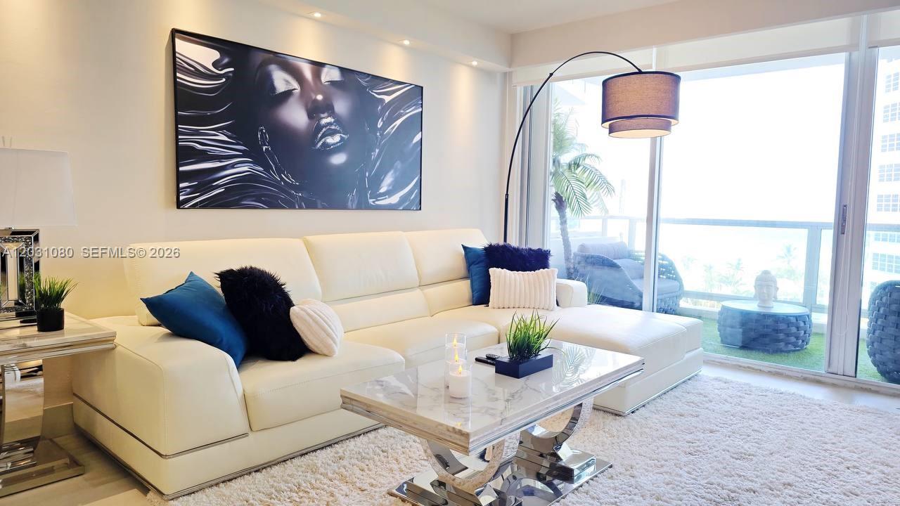 A modern living room features a white leather sectional, marble coffee table, and large wall art — 5151 Collins Ave # 726, Miami Beach FL 33140, MIAMI BEACH, FL