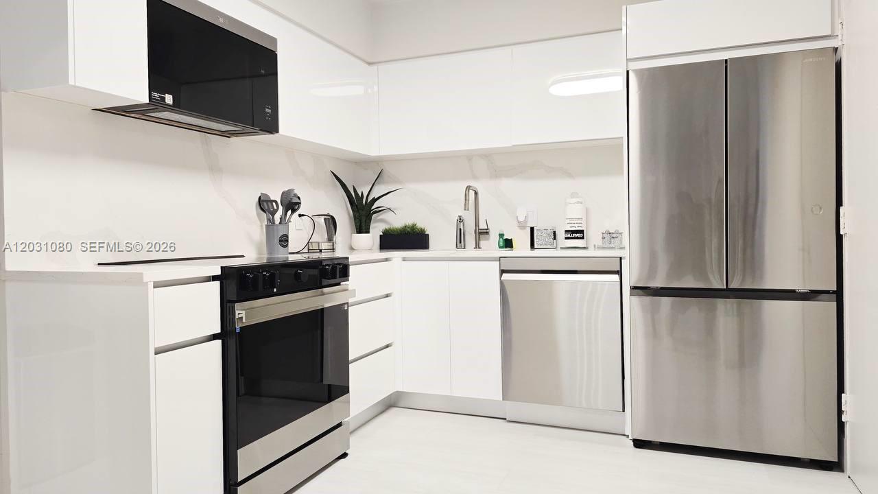 A modern kitchen features white cabinets, stainless steel appliances, and a marble-patterned backsplash — 5151 Collins Ave # 726, Miami Beach FL 33140, MIAMI BEACH, FL