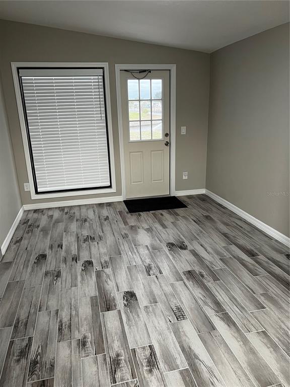 A room with gray wood-look tile flooring, a window with blinds, and an exterior door — 21248 EDGEWATER DRIVE, PORT CHARLOTTE, FL
