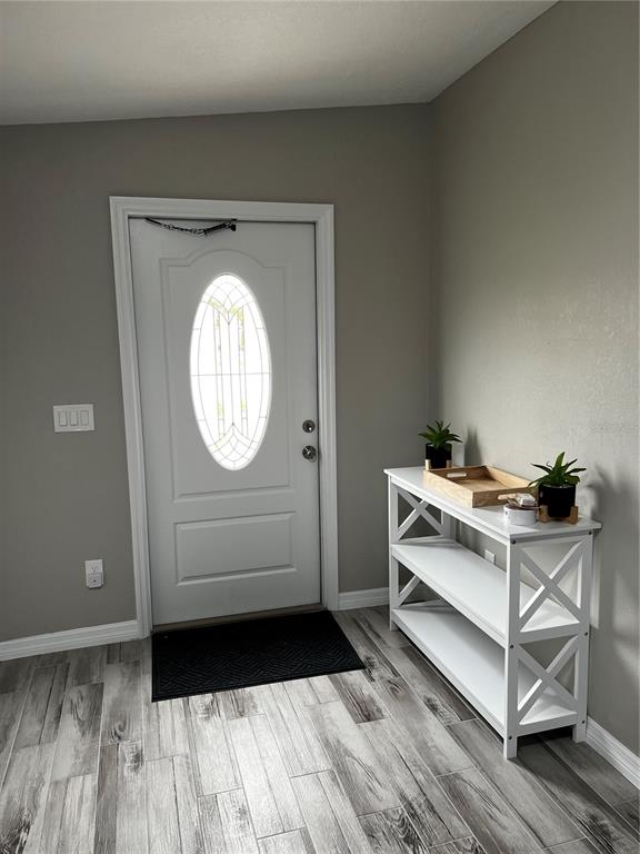 An entryway features a white front door, gray walls, wood-look tile flooring, and a white console table — 21248 EDGEWATER DRIVE, PORT CHARLOTTE, FL
