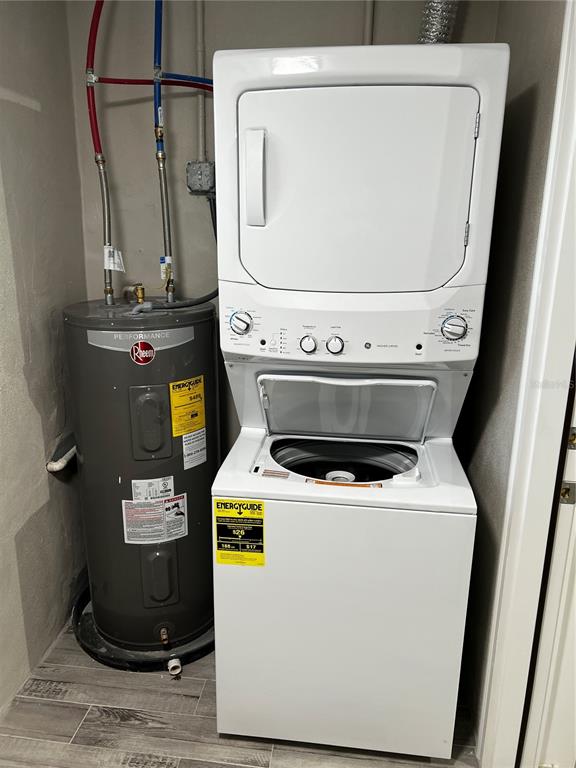 A utility closet contains a stacked washer-dryer unit next to a Rheem water heater — 21248 EDGEWATER DRIVE, PORT CHARLOTTE, FL