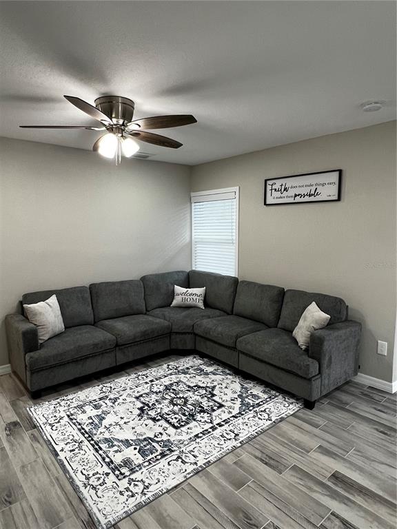 A living room features a gray sectional sofa, a patterned area rug, and a ceiling fan — 21248 EDGEWATER DRIVE, PORT CHARLOTTE, FL