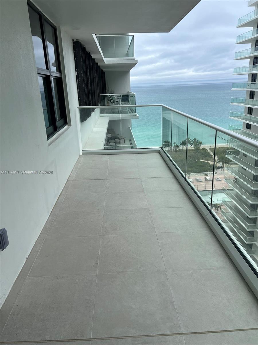 A balcony with large gray floor tiles and a glass railing overlooks the ocean — 9801 Collins Ave # 17J, Bal Harbour FL 33154, BAL HARBOUR, FL