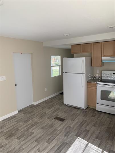 A kitchen features light wood cabinets, a white refrigerator, a white stove, and gray flooring — 2854 LAKE ALFRED ROAD UNIT 3, WINTER HAVEN, FL