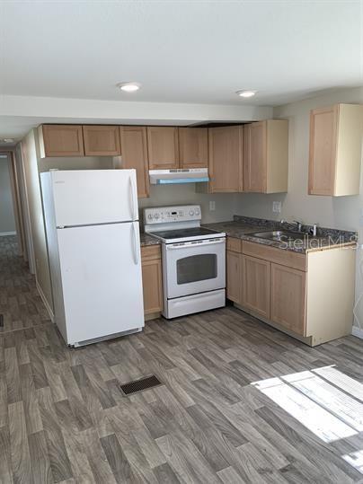 A kitchen features light wood cabinets, white appliances, and gray wood-look flooring — 2854 LAKE ALFRED ROAD UNIT 3, WINTER HAVEN, FL