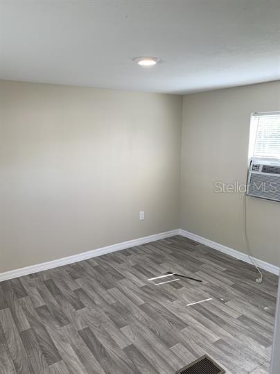 An empty room with light-colored walls, gray wood-look flooring, and a window air conditioning unit — 2854 LAKE ALFRED ROAD UNIT 3, WINTER HAVEN, FL