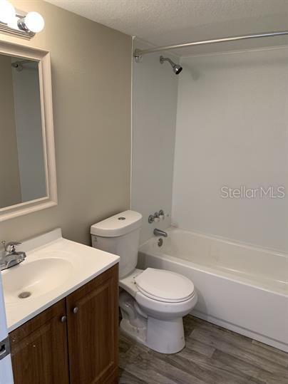 A bathroom featuring a wood vanity, a white toilet, and a shower-tub combination — 2854 LAKE ALFRED ROAD UNIT 3, WINTER HAVEN, FL