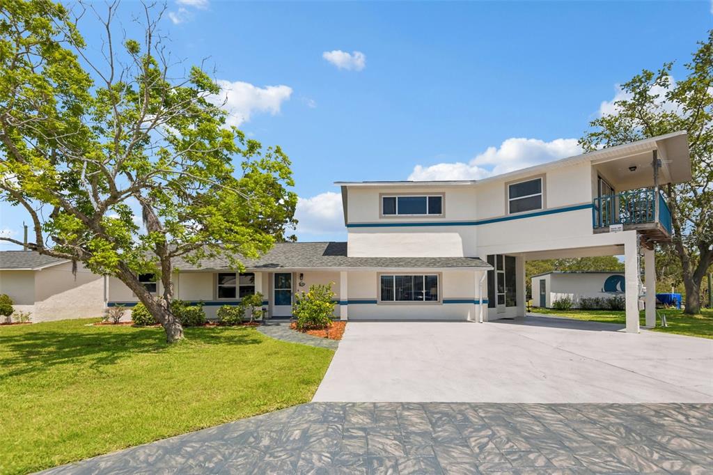 A two-story house with a white exterior, blue trim, and a covered carport area — 8212 HAYWARD LANE, PORT RICHEY, FL