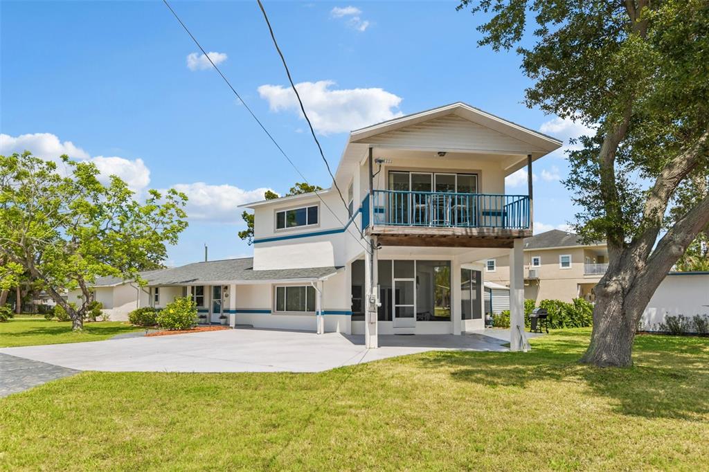 A two-story house with a white exterior, a second-floor balcony, and a screened-in ground level — 8212 HAYWARD LANE, PORT RICHEY, FL
