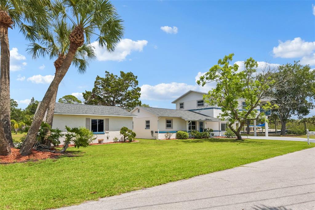 A multi-level house with a detached garage sits on a grassy lot with palm trees — 8212 HAYWARD LANE, PORT RICHEY, FL