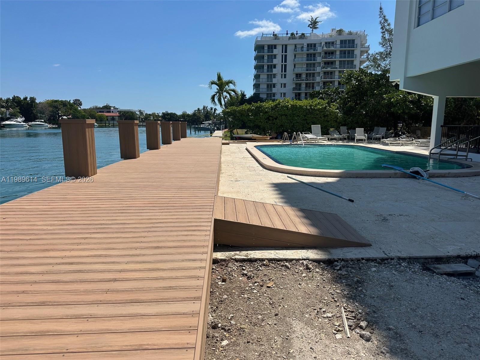 A wooden dock leads to a swimming pool area beside a waterfront building — 9341 E Bay Harbor Dr # 6C, Bay Harbor Islands FL 33154, BAY HARBOR ISLANDS, FL