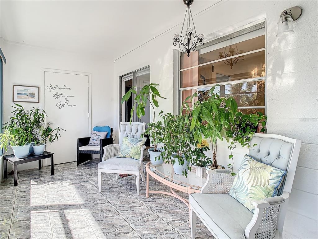 A sunroom features tiled floors, potted plants, a glass-topped table, and several chairs — 3100 HARTFORD STREET N UNIT 227, ST PETERSBURG, FL