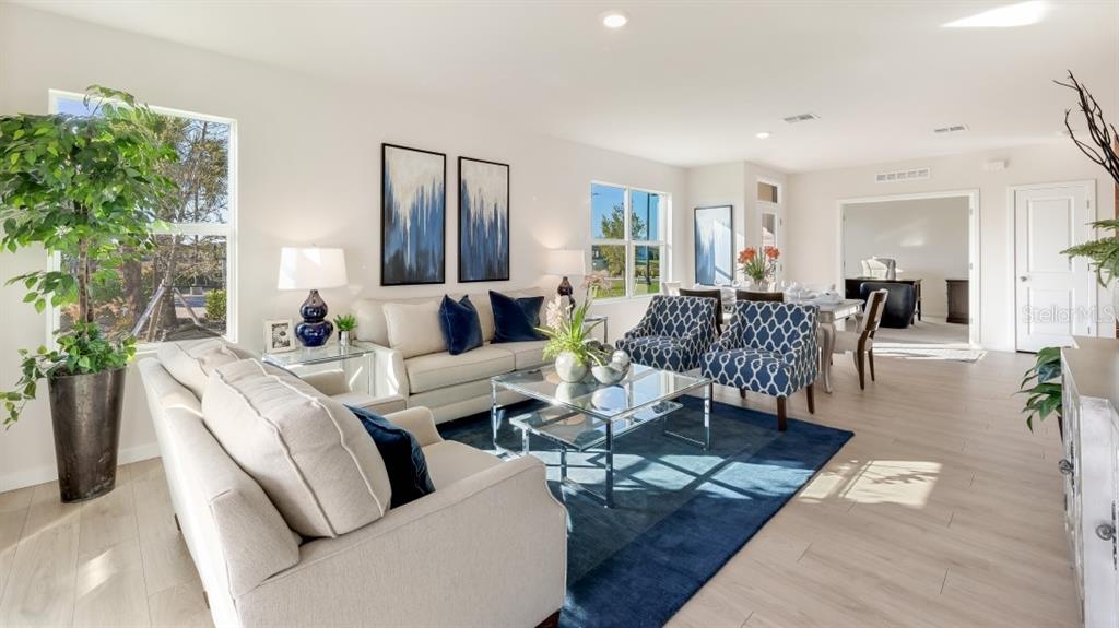 A living room features light-colored sofas, blue patterned armchairs, a glass coffee table, and flooring — 16330 BRIDLE RIDGE STREET, PORT CHARLOTTE, FL