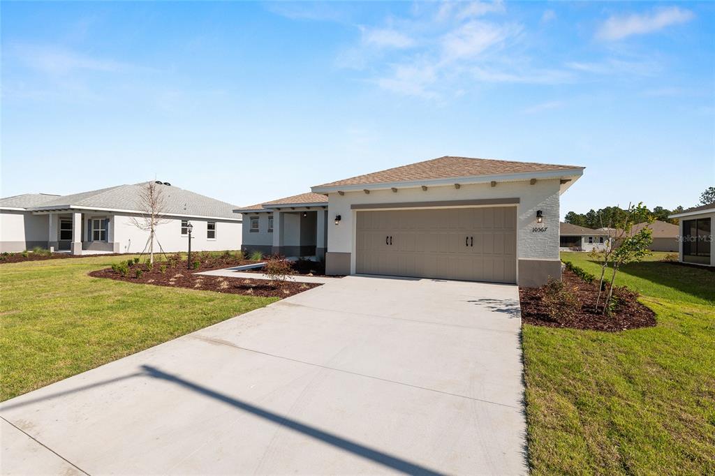 A single-story house with a beige garage and a concrete driveway under a blue sky — 10567 SW 101ST LANE ROAD, OCALA, FL