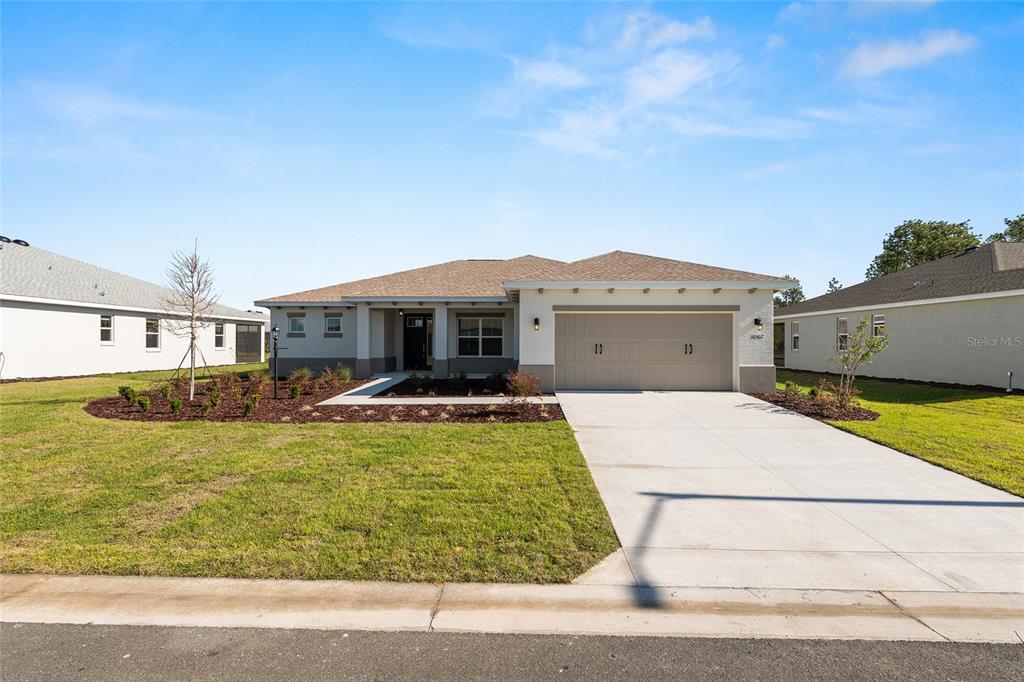 A single-story suburban house with a tan stucco exterior and a two-car garage — 10567 SW 101ST LANE ROAD, OCALA, FL