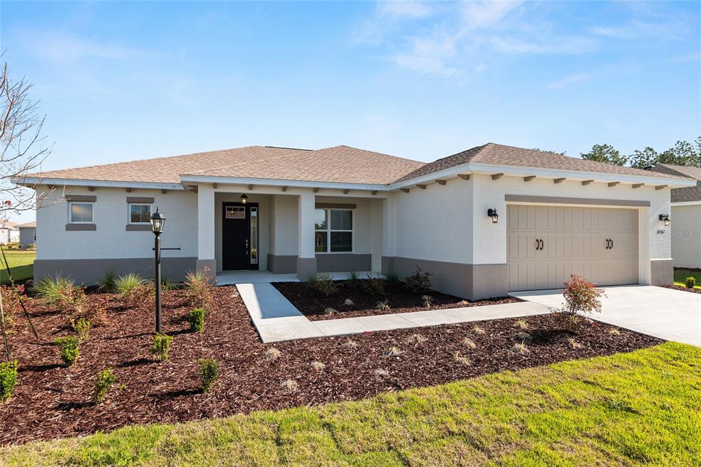 A single-story house with a white stucco exterior, a two-car garage, and a landscaped yard — 10567 SW 101ST LANE ROAD, OCALA, FL