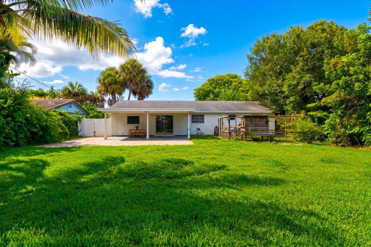 A backyard view of a single-story house with a covered patio and a grassy lawn — 583 NW 12th Terrace, Boca Raton FL 33486, BOCA RATON, FL