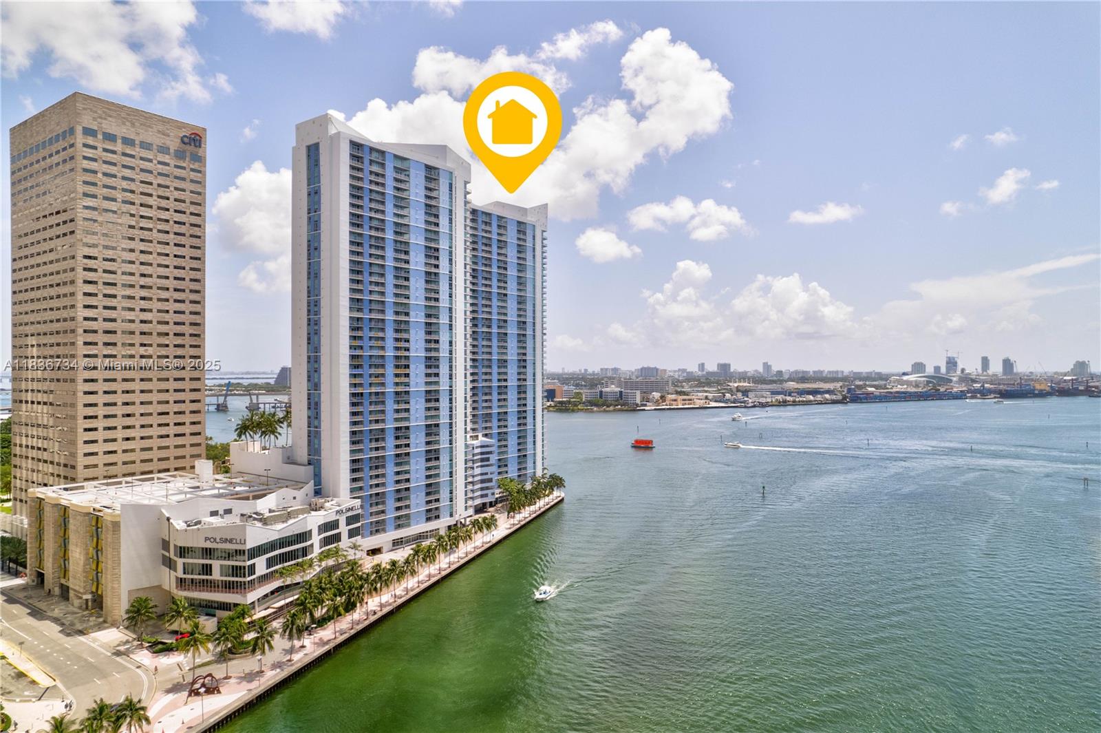 An aerial view shows a tall blue and white residential tower situated along a waterfront — 335 S Biscayne Blvd # 3108, Miami FL 33131, MIAMI, FL
