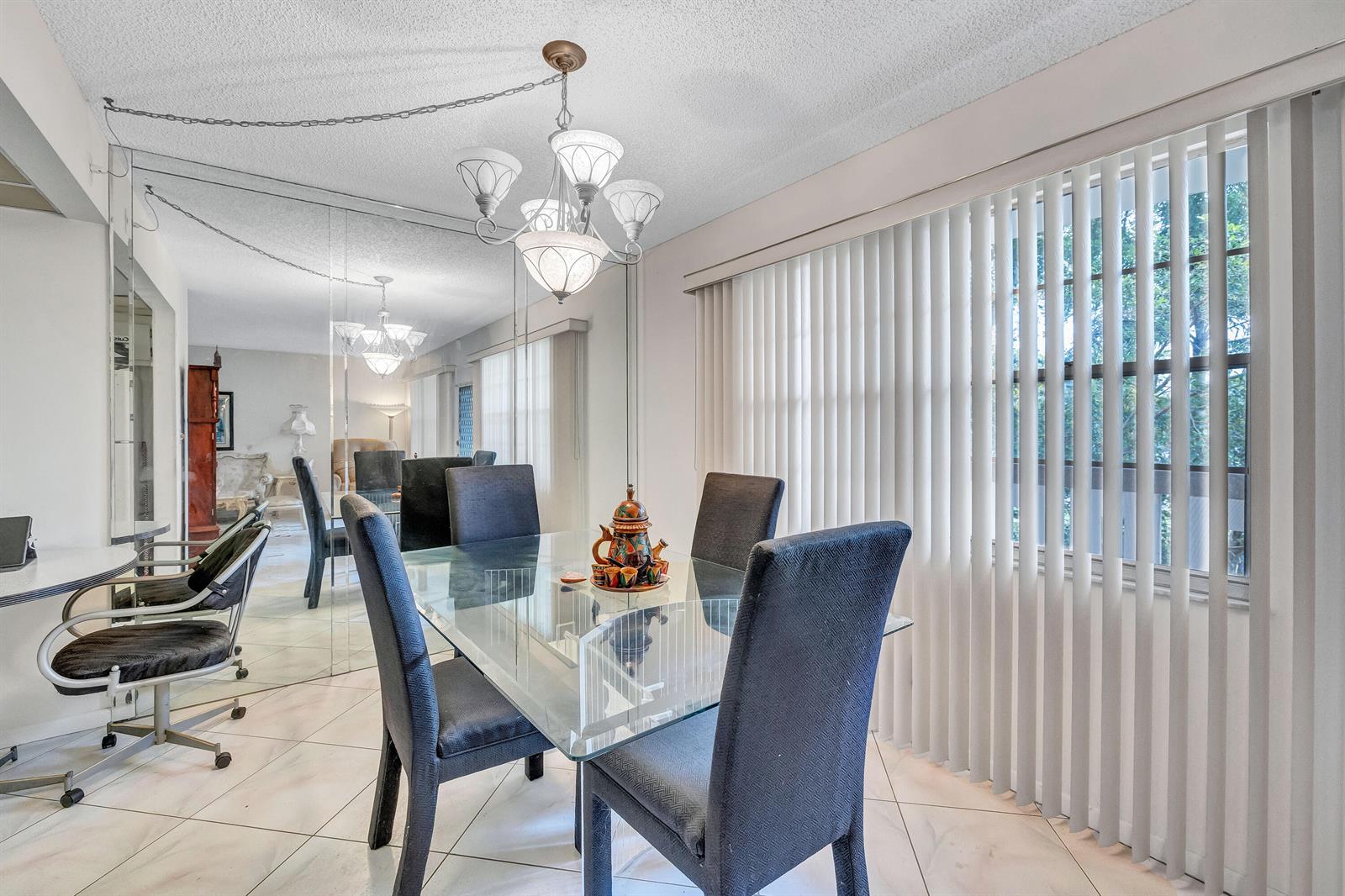 A dining room features a glass table, dark chairs, a chandelier, and a mirrored wall — 1902 Bermuda Circle # L2, Coconut Creek FL 33066, COCONUT CREEK, FL