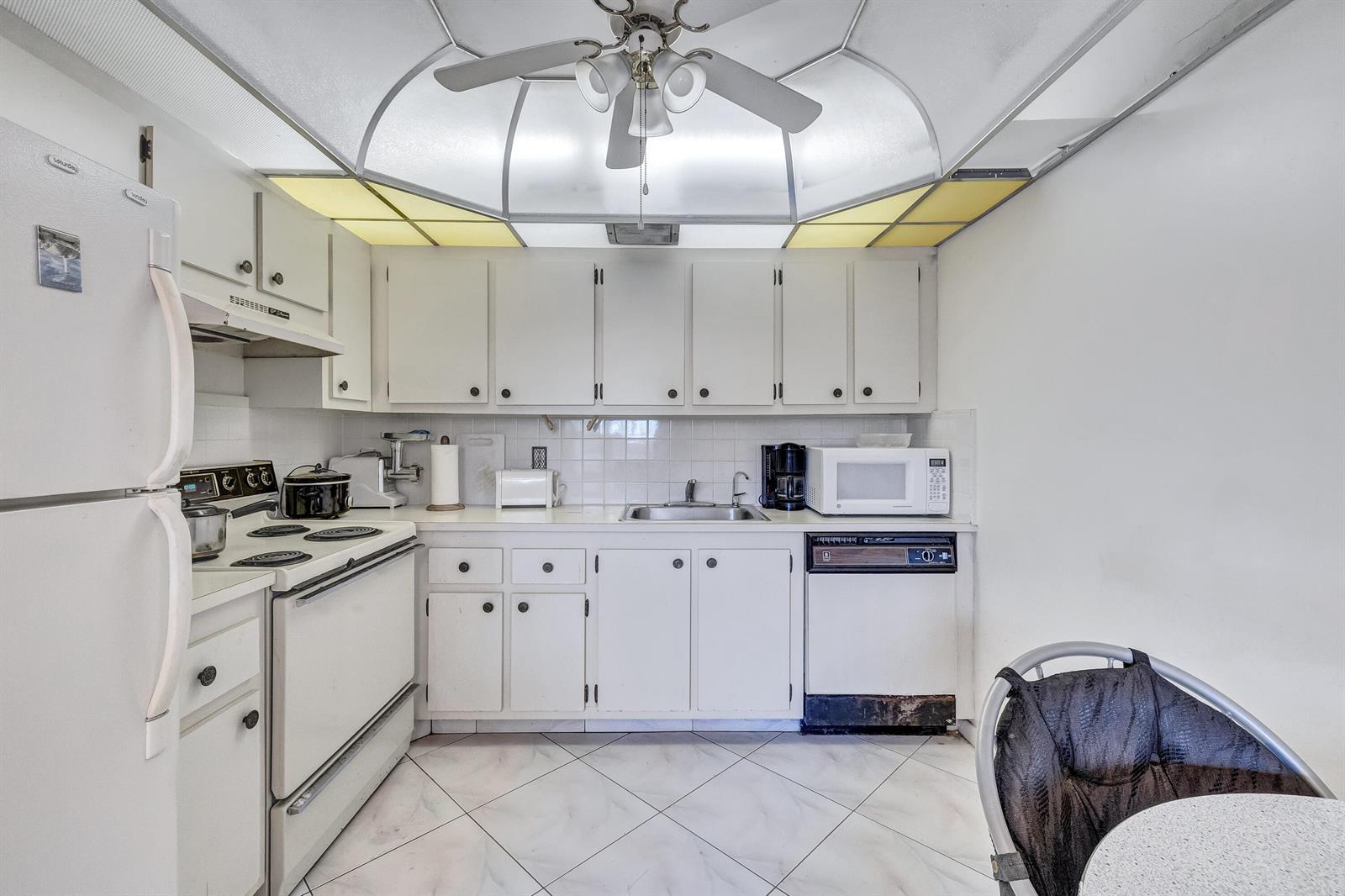 A kitchen featuring white cabinets, white appliances, a tiled floor, and a ceiling fan — 1902 Bermuda Circle # L2, Coconut Creek FL 33066, COCONUT CREEK, FL