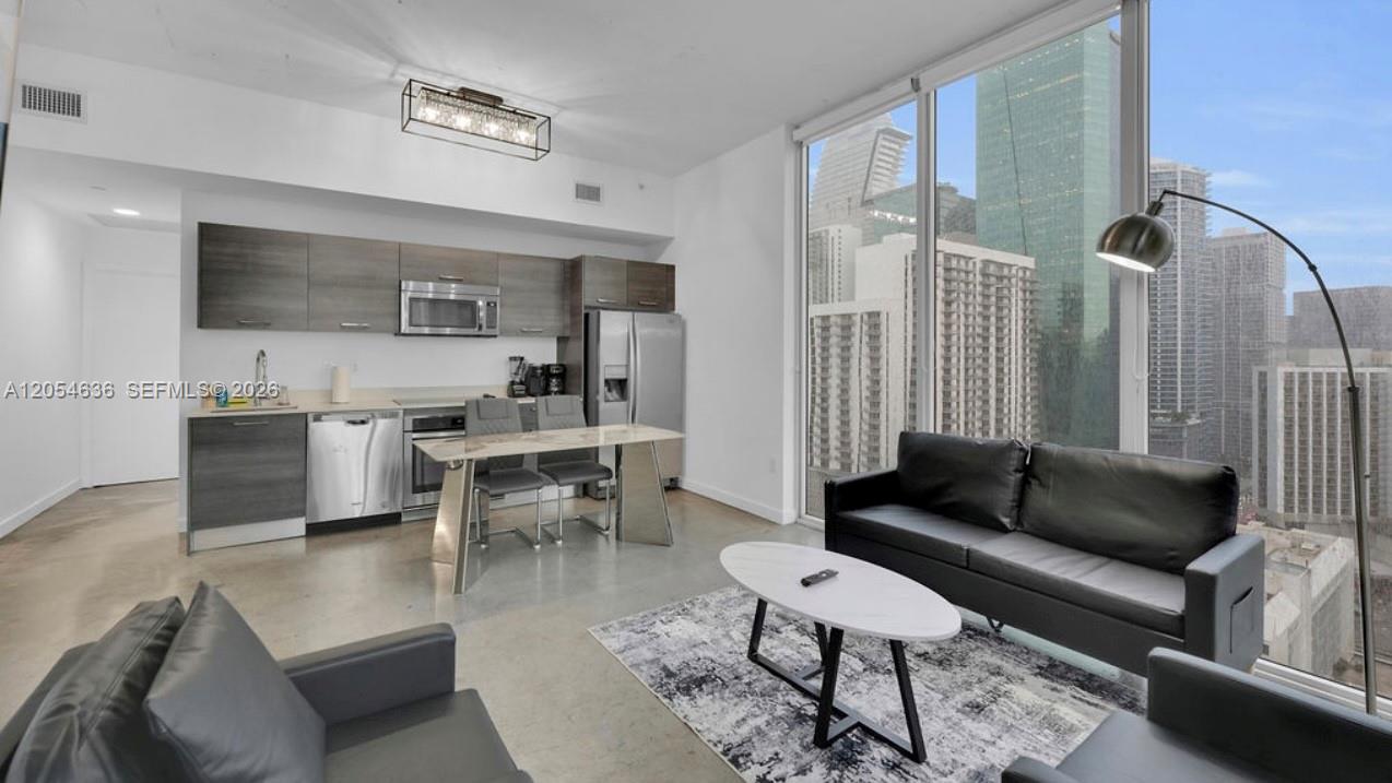 A modern kitchen and living area with concrete floors, stainless steel appliances, and floor-to-ceiling windows — 151 SE 1st St # 2411, Miami FL 33131, MIAMI, FL