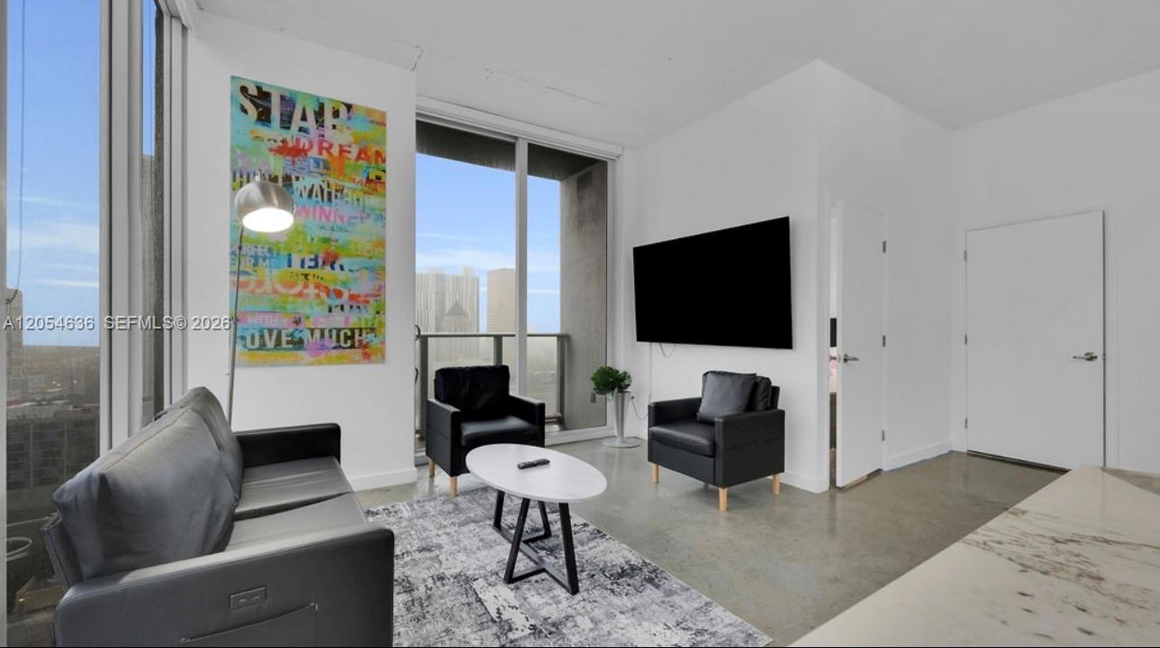 A modern living room features a grey sofa, two black armchairs, and colorful wall art — 151 SE 1st St # 2411, Miami FL 33131, MIAMI, FL