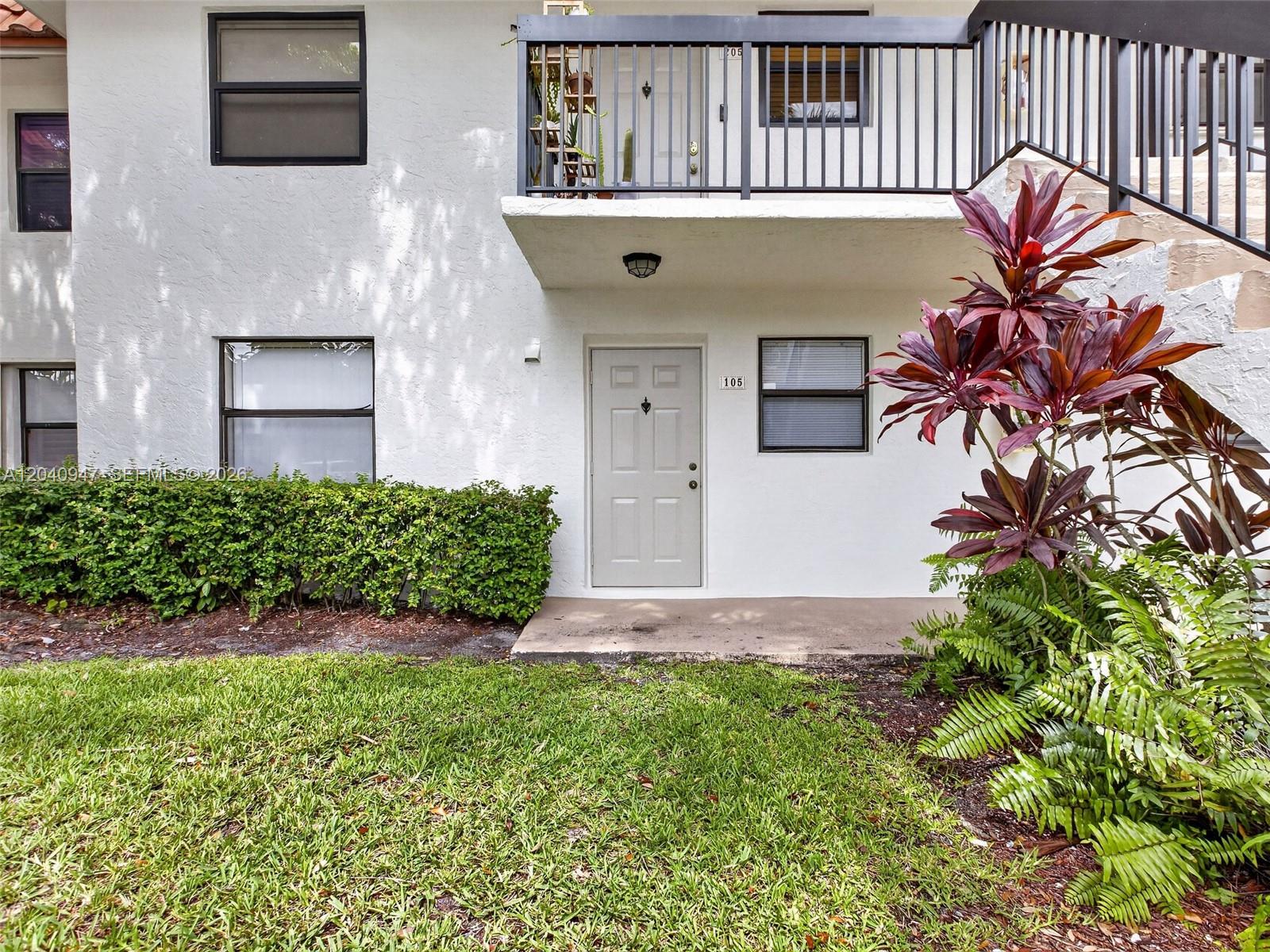 The exterior of a two-story apartment building features a ground-level unit with a numbered door — 15718 E Waterside Cir # 105, Sunrise FL 33326, SUNRISE, FL