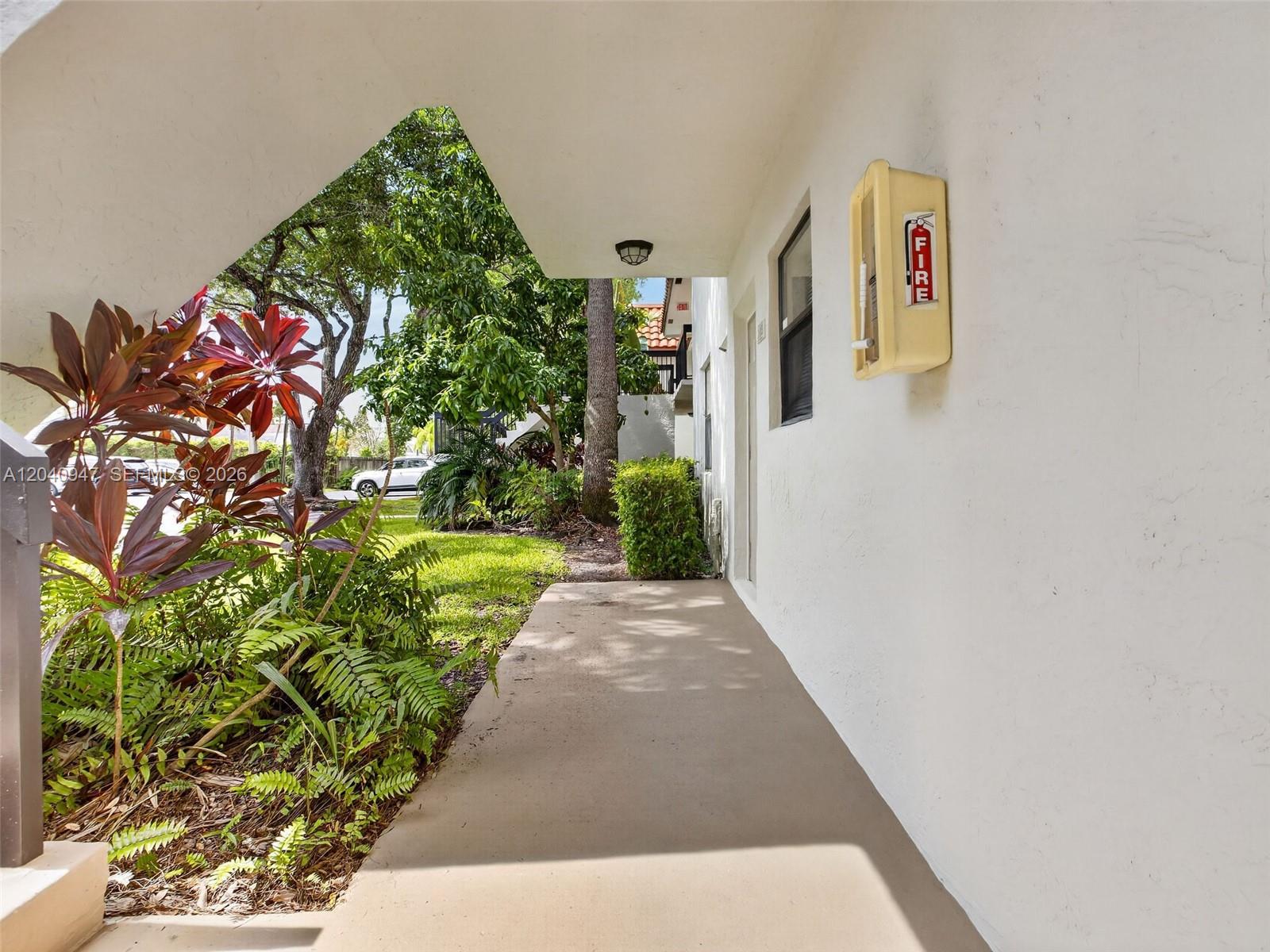 A concrete walkway leads past a building exterior with a wall-mounted fire extinguisher cabinet — 15718 E Waterside Cir # 105, Sunrise FL 33326, SUNRISE, FL