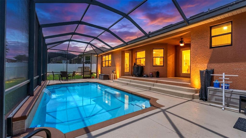 A screened-in patio features a rectangular swimming pool with a waterfall and concrete steps — 2873 KINSLEY DRIVE, LAKELAND, FL