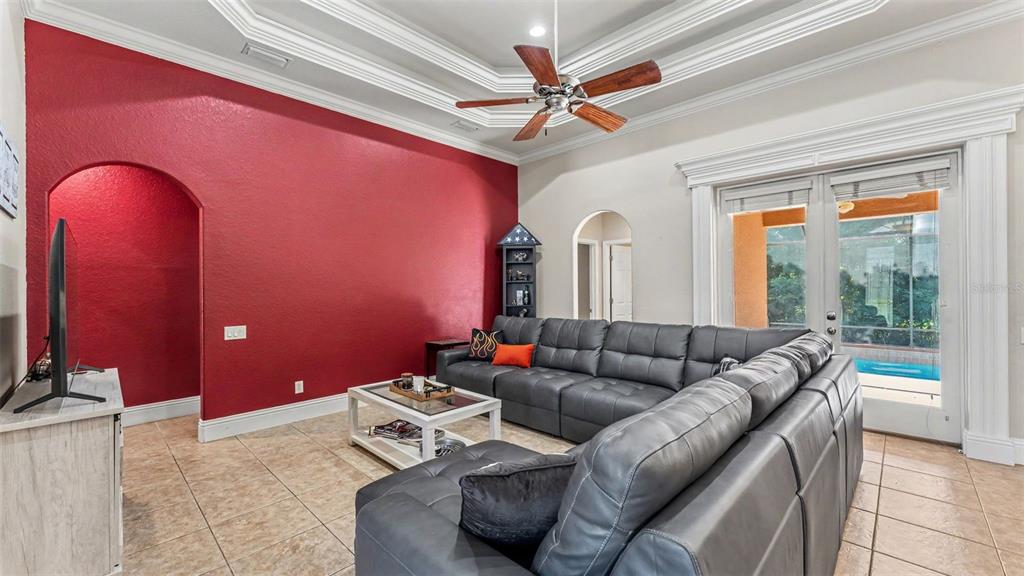 A living room features a red accent wall, gray sectional sofa, and a ceiling fan — 2873 KINSLEY DRIVE, LAKELAND, FL