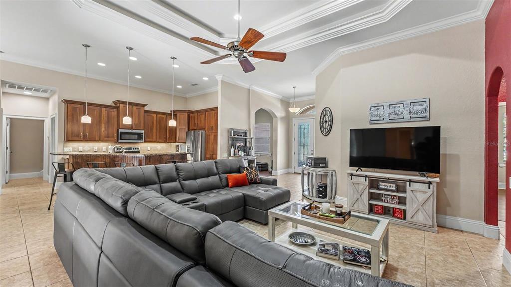 A living room with a grey sectional sofa, coffee table, and television faces an open kitchen — 2873 KINSLEY DRIVE, LAKELAND, FL