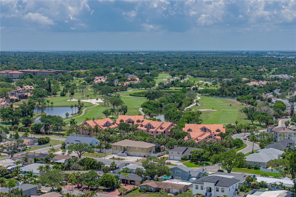 An aerial view of a residential neighborhood featuring multi-story buildings overlooking a golf course — 6717 CARDINAL DRIVE S, ST PETERSBURG, FL