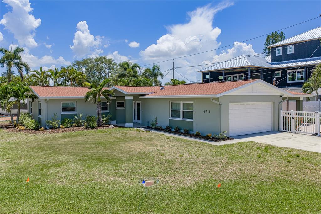 A single-story house with a light green exterior, a white garage door, and a shingled roof — 6717 CARDINAL DRIVE S, ST PETERSBURG, FL