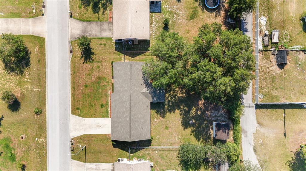 An aerial view shows a house with a gray roof surrounded by trees and grass — 4008 SE 61 PLACE, OCALA, FL