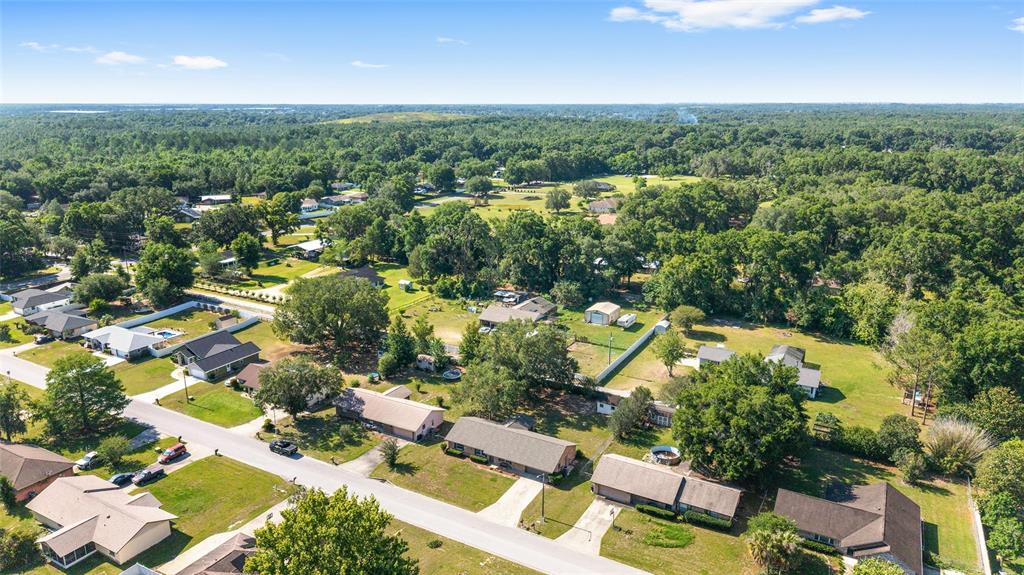 An aerial view shows a suburban neighborhood with houses, driveways, and surrounding wooded areas — 4008 SE 61 PLACE, OCALA, FL