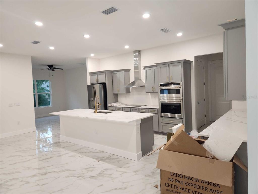 A modern kitchen features gray cabinets, a white marble island, and stainless steel appliances — 5413 DELTONA BOULEVARD, SPRING HILL, FL