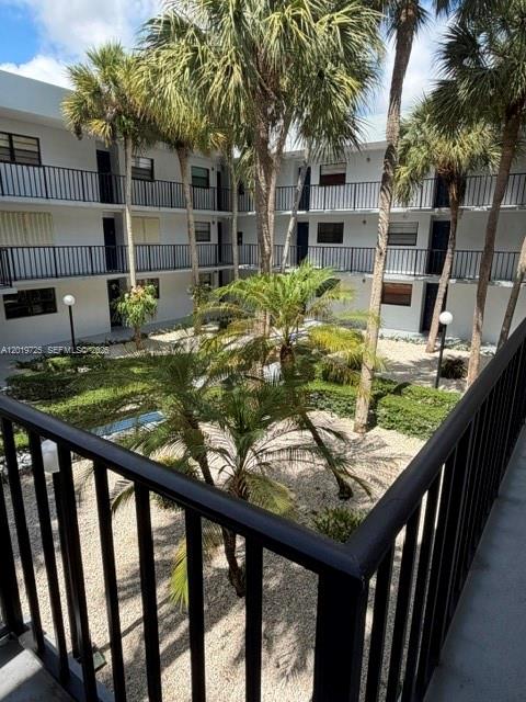 A view from a balcony overlooking a courtyard with palm trees and apartment buildings — 10825 SW 112 AV # 215, Miami FL 33176, MIAMI, FL