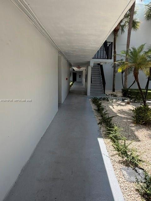An outdoor concrete walkway leads toward a staircase between two white building structures — 10825 SW 112 AV # 215, Miami FL 33176, MIAMI, FL