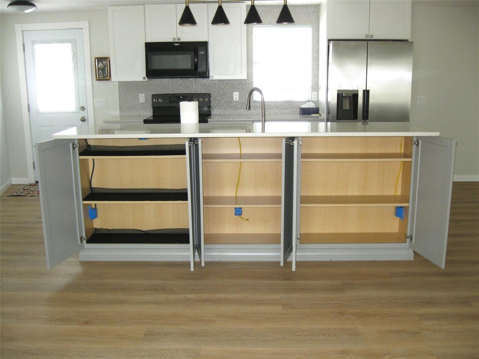 A kitchen island with open cabinet doors reveals interior shelving and electrical outlets — 4800 SE Federal Highway, Stuart FL 34997, STUART, FL