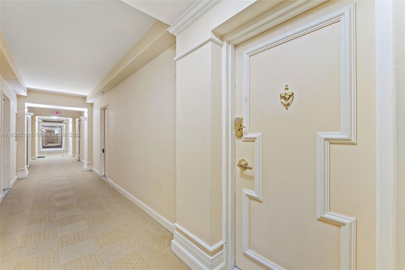 A long, beige-carpeted hallway features a door with a gold knocker and electronic lock — 5700 Collins Ave # 5B, Miami Beach FL 33140, MIAMI BEACH, FL