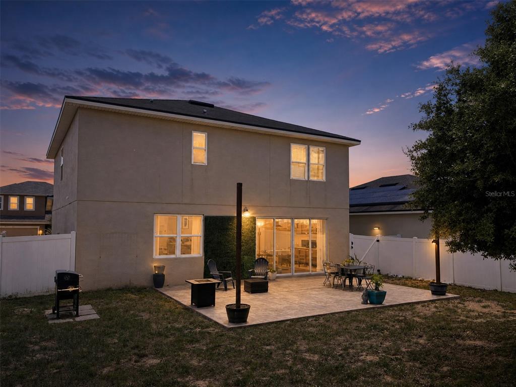 The exterior of a two-story house features a paved patio, a grill, and a fenced yard — 324 BUCHANNAN DRIVE, DAVENPORT, FL
