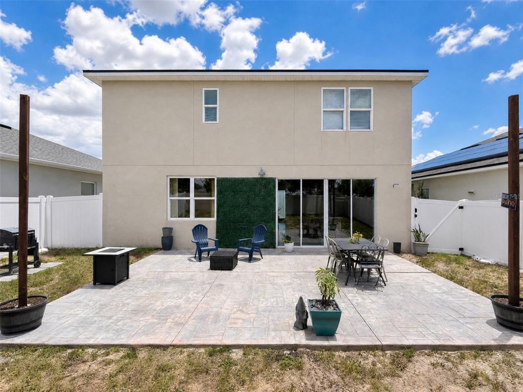 A backyard features a stamped concrete patio with outdoor furniture and a green wall panel — 324 BUCHANNAN DRIVE, DAVENPORT, FL